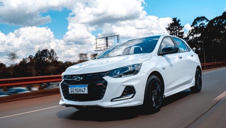 Chevrolet Onix RS branco hatch compacto na estrada de frente