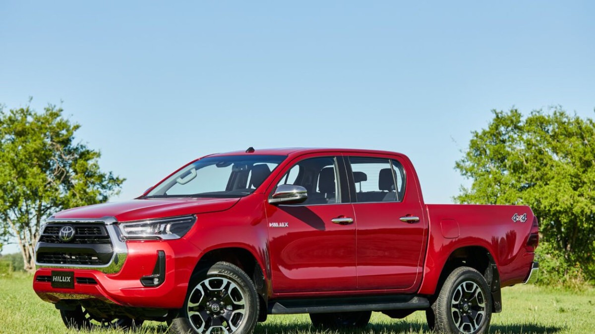 Toyota Hilux 2022 vermelha visto da lateral na grama.