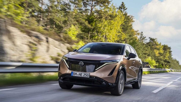 Nissan Ariya de frente em movimento em estrada asfaltada e arborizada