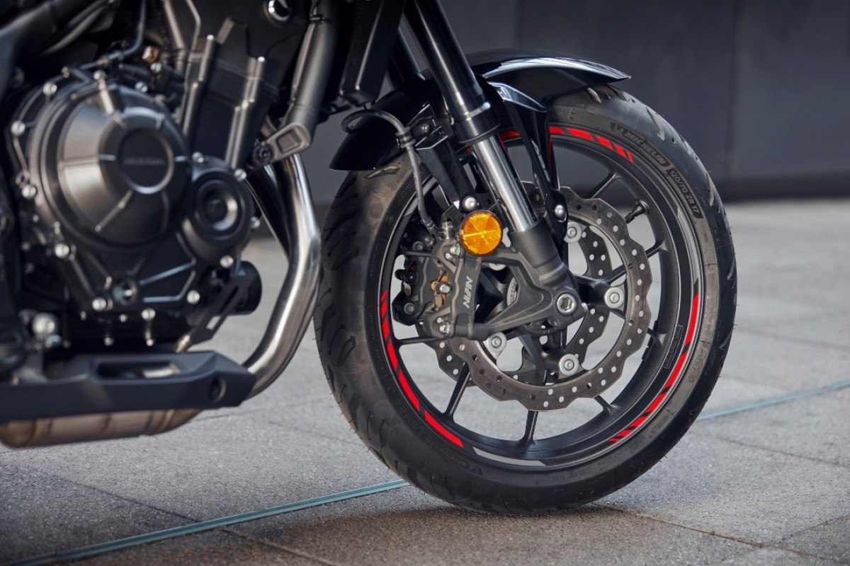 Honda CB 500 Hornet modelo 2024 branca preto vermelho detalhe roda dianteira no calçamento
