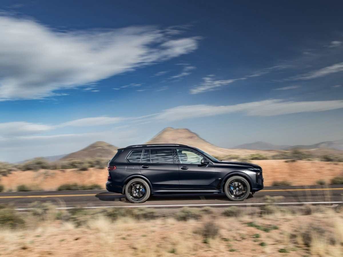 BMW X7 M60i modelo 2024 preto de lateral em movimento no asfalto.jpg