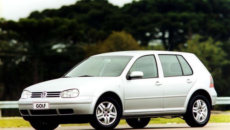 Volkswagen Golf GTI 2003 prata de frente estacionado com vegetação ao fundo