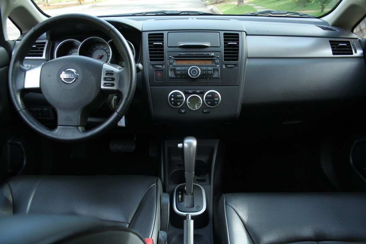 Nissan Tiida SL 1.8 Flex modelo 2010 vermelho estático interior painel e bancos dianteiros no asfalto