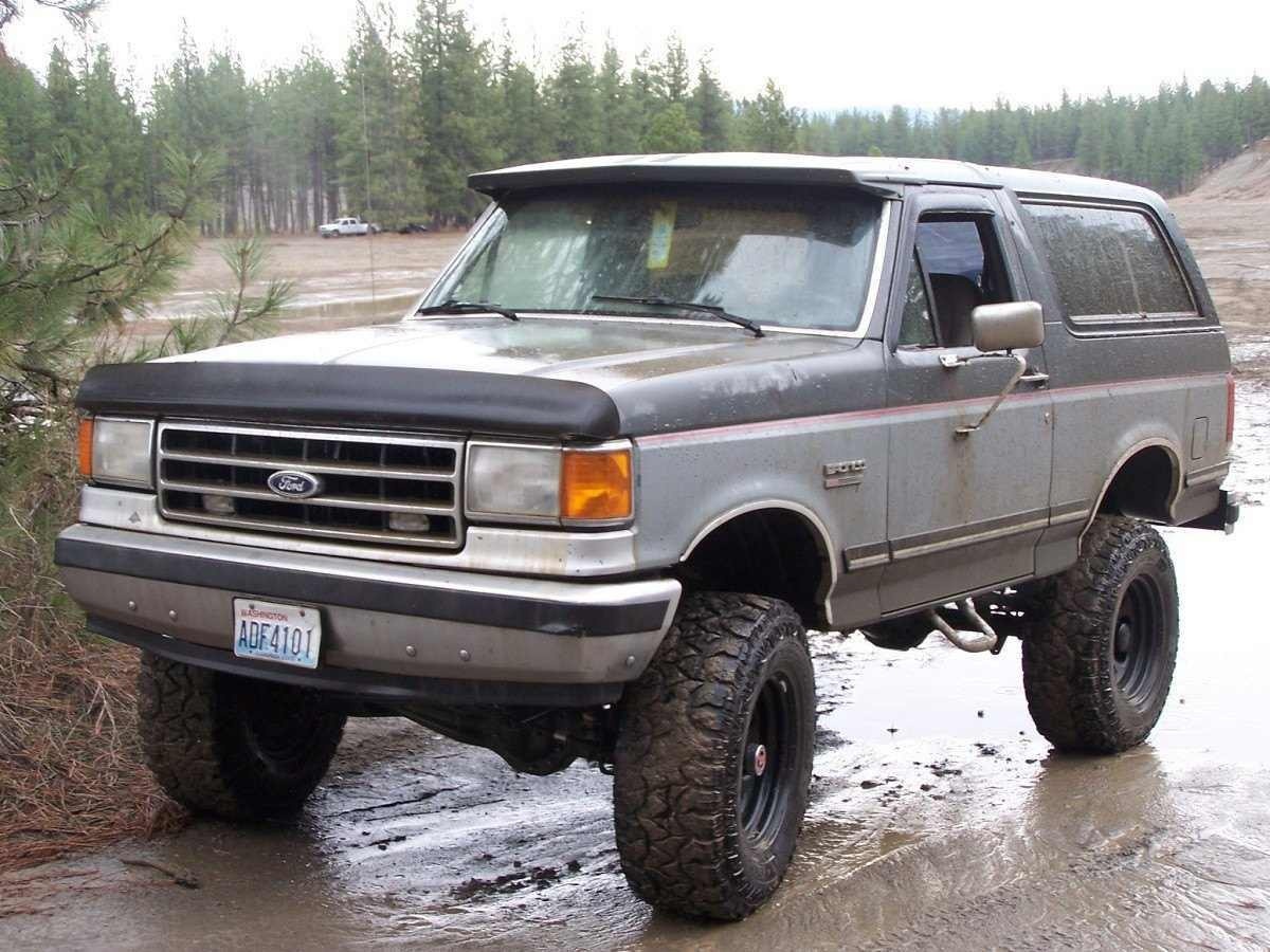 1989 Ford Bronco na cor marrom está estacionado em uma poça de barro.