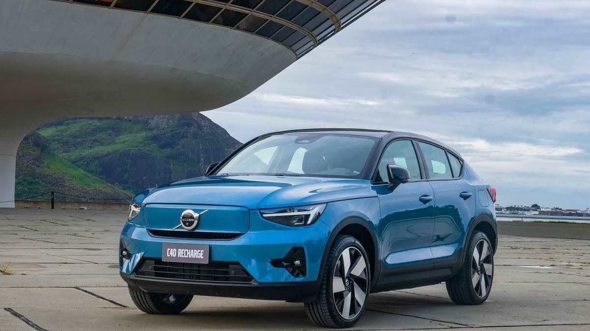 Volvo C40 azul parado em chão de pedra com edificio ao fundo e céu azul