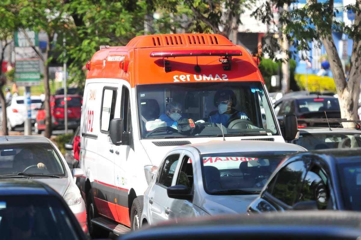 Ambulância branca e laranja em meio a vários veículos no trânsito