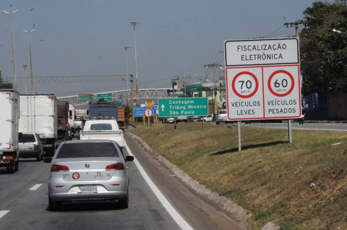 Carros e caminhões trafegando em rodovia em Minas Gerais com placa de sinalização de velocidade máxima permitida