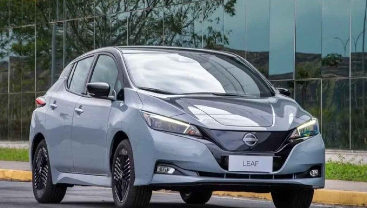 Nissan Leaf trafega em rua com pr&eacute;dio espelhado ao fundo.