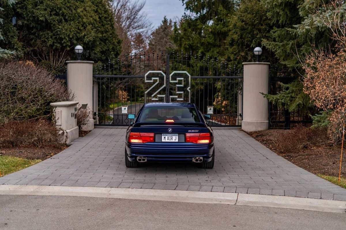 BMW 850i 1991 vista por trás está estacionada em frente a portão em que se lê o número 23 usado pelo jogador Michael Jordan.