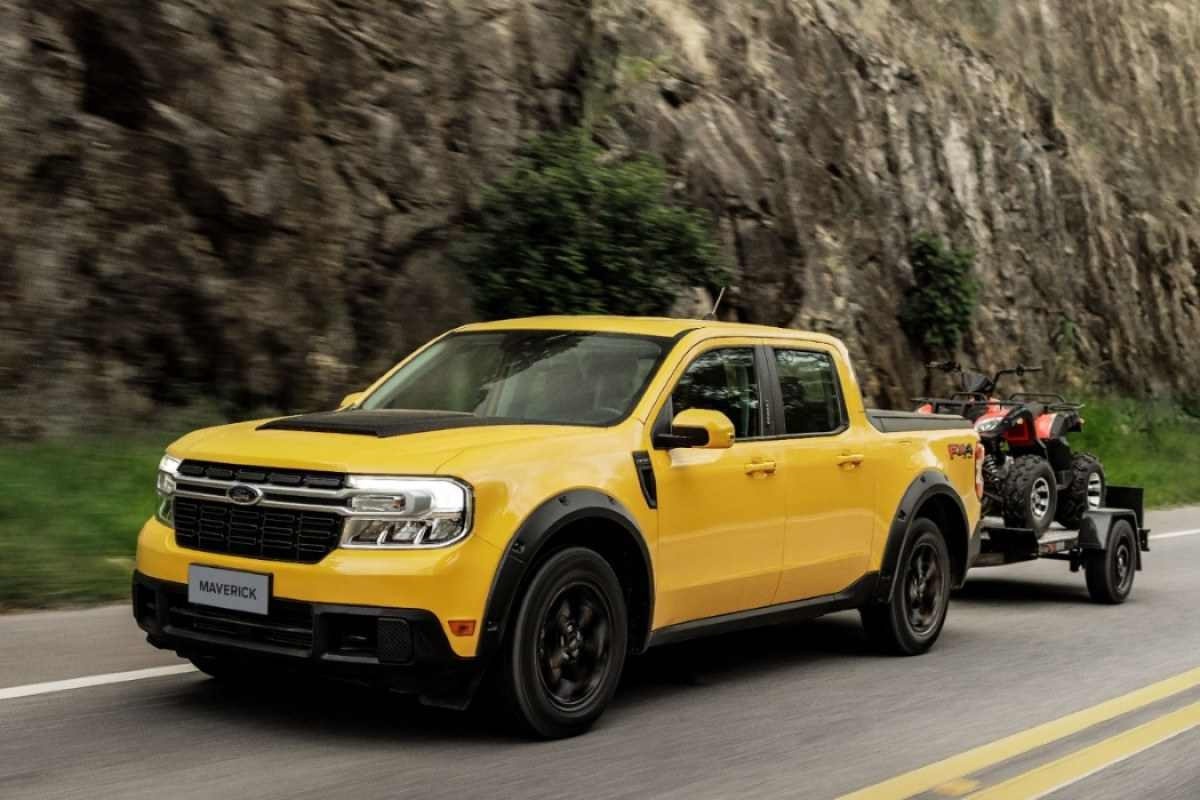 Ford Maverick Lariat FX4 amarela de frente em movimento puxando carretinha com quadriciclo no asfalto