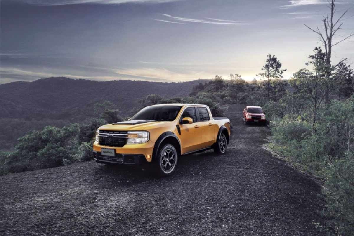 Ford Maverick Lariat FX4 amarela de frente em primeiro plano e vermelha ao fundo ambas estáticas na terra