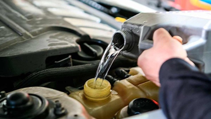 Galão com água sendo despejado no sistema de arrefecimento do motor