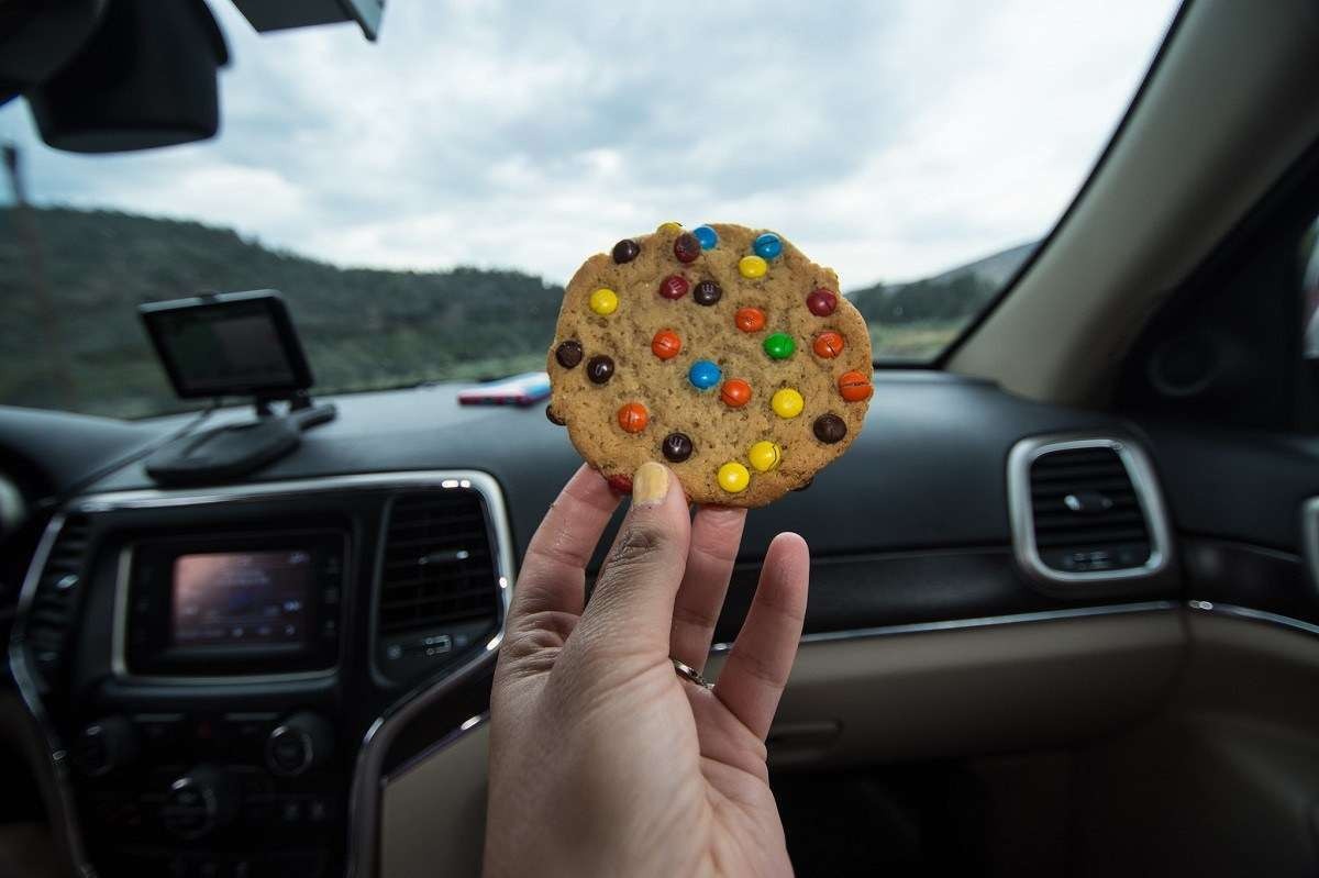 Mão segura um cookie dentro de um carro.