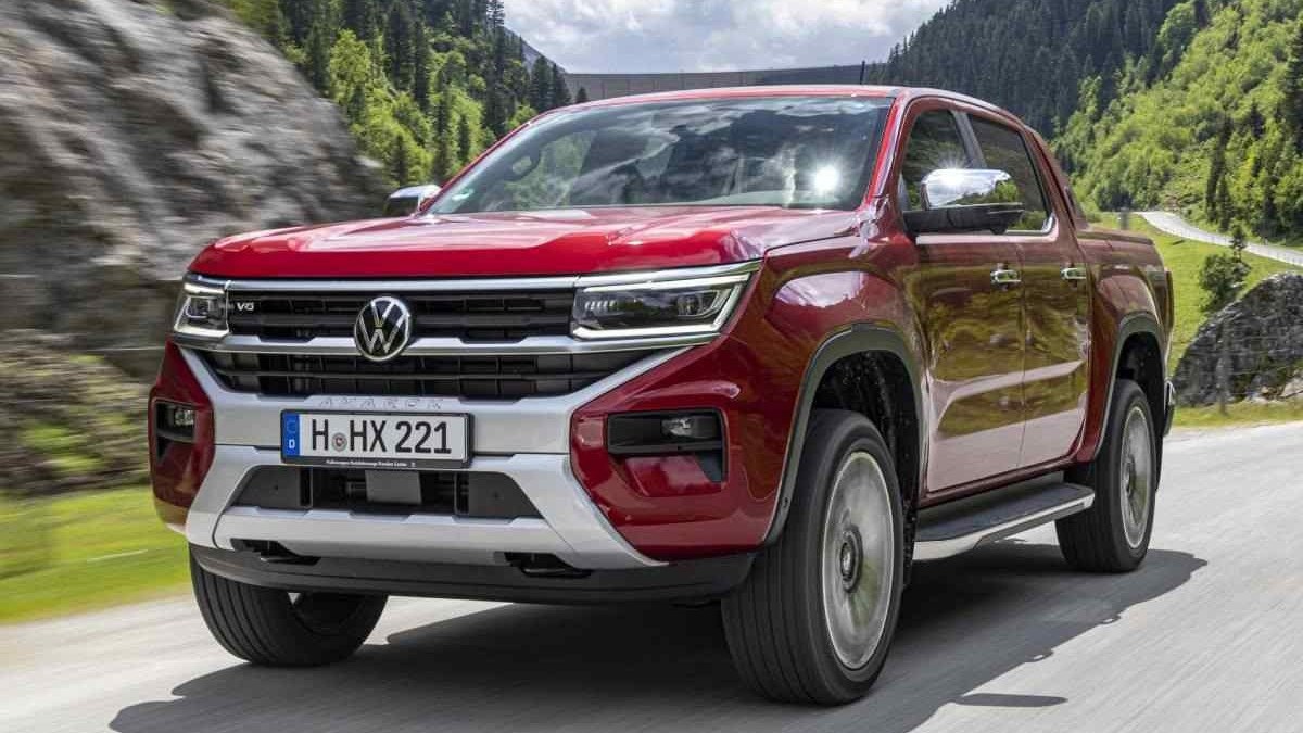 Volkswagen Amarok 2023 vermelha de frente em movimento em rodovia asfaltada com montanhas ao fundo