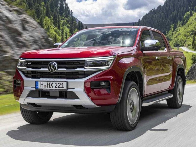 Volkswagen Amarok 2023 vermelha de frente em movimento em rodovia asfaltada com montanhas ao fundo