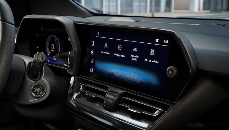 Vista do interior do Novo Spin 2025, os detalhes estão em preto e a central multimídia está ligada com tela de fundo azul.