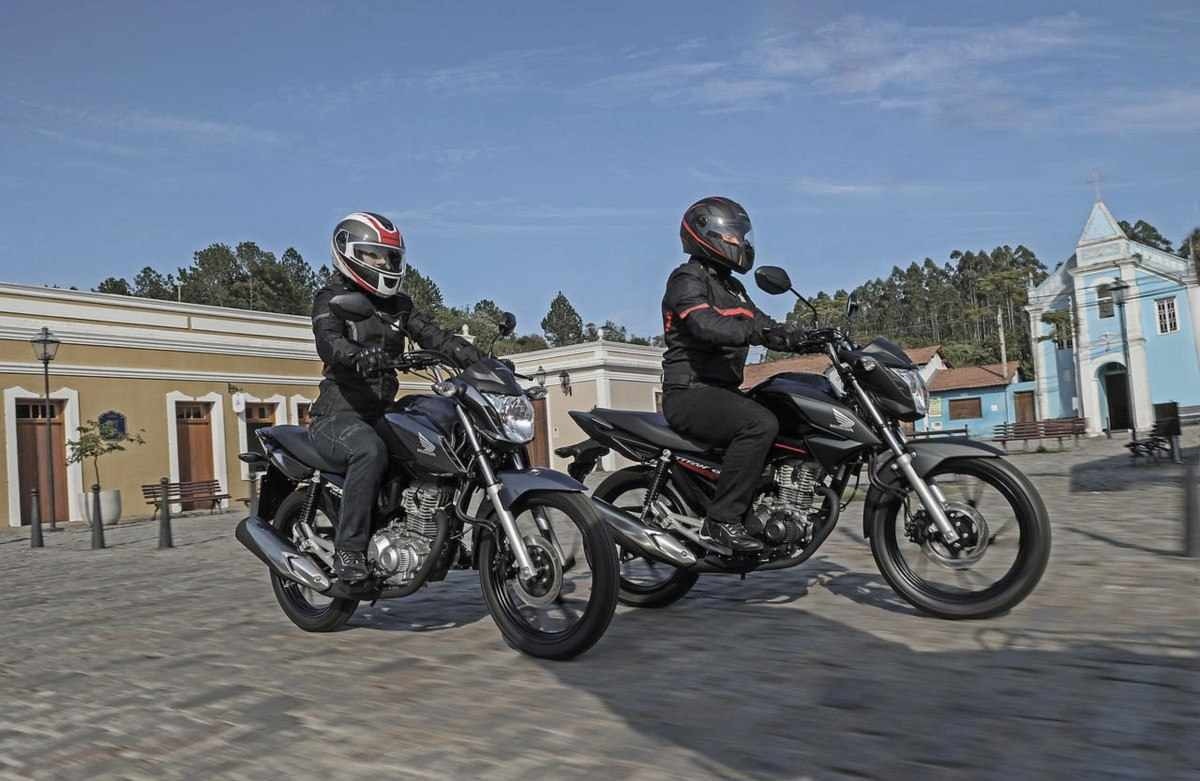 Honda CG 160 preta duas unidades de frente em movimento no calçamento