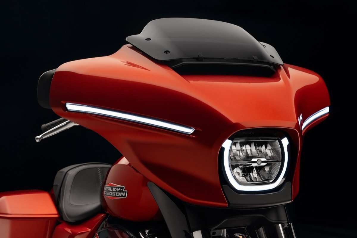 Harley-Davidson Street Glide modelo 2024 laranja avermelhado detalhe da carenagem e farol em LED de frente no estúdio
