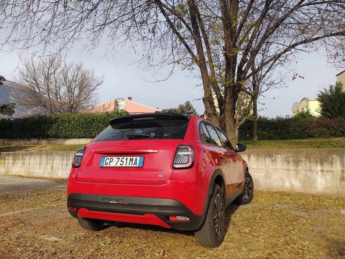 Fiat 600 vermelho de traseira estacionado sobre folhas