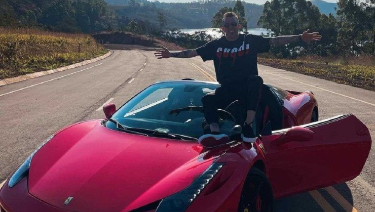 Bernard sentado em capô de Ferrari F458 Spider vermelha.