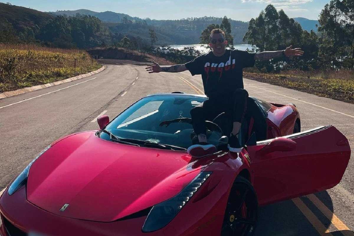 Bernard sentado em capô de Ferrari F458 Spider vermelha.