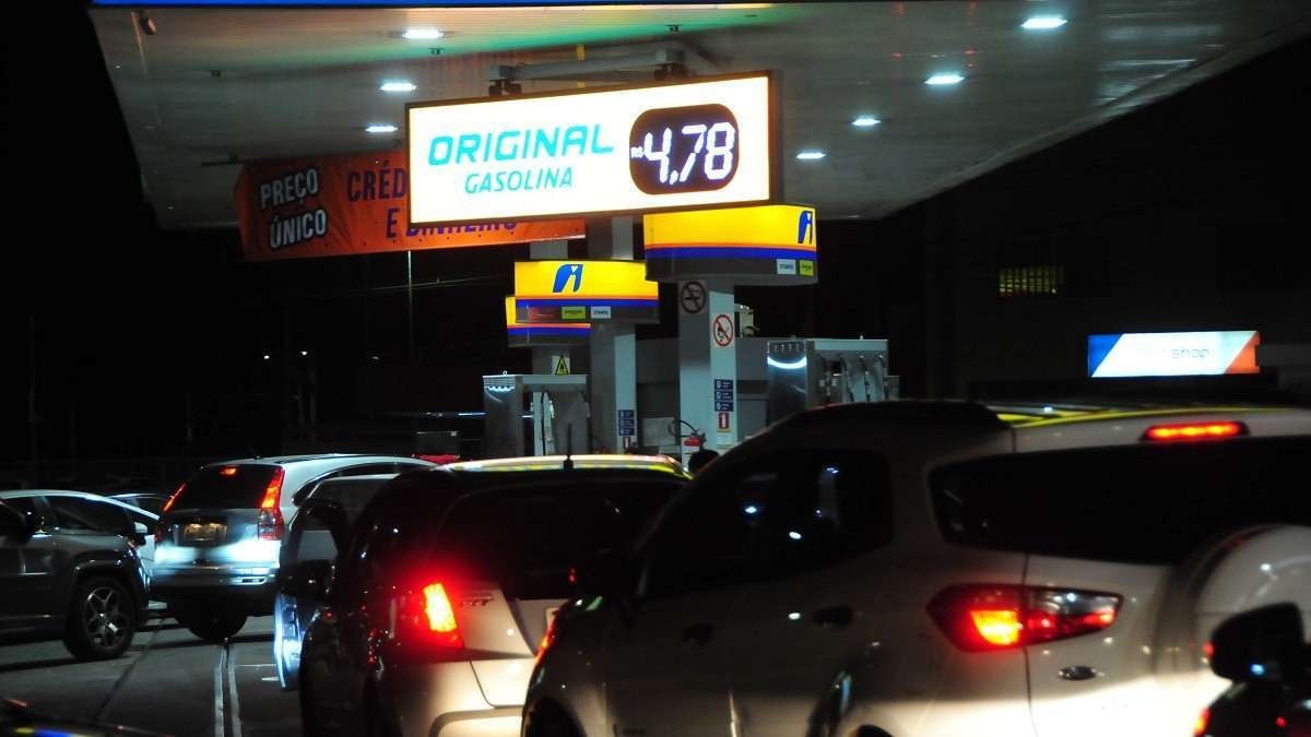 Na foto, posto de combustível a noite com carros enfileirados para abastecer.