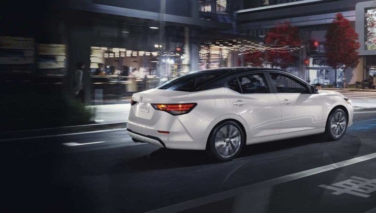 Nissan Sentra branco visto pela lateral andando em rua.