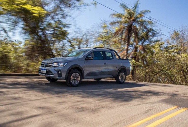 Volkswagen Saveiro Extreme 1.6 2023 cinza em movimento com fundo de plantas