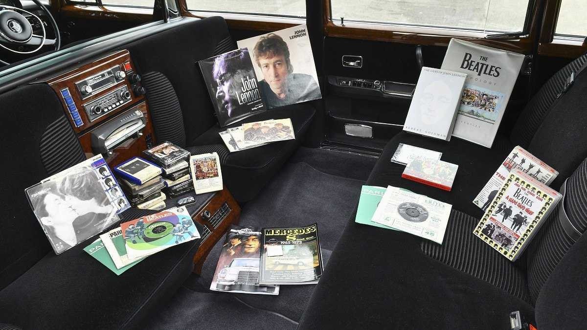 Interior da Mercedes-Benz 600 Pullman com foco no toca-discos, há espalhado pelo chão e bancos vinis dos Beatles e de John Lennon.