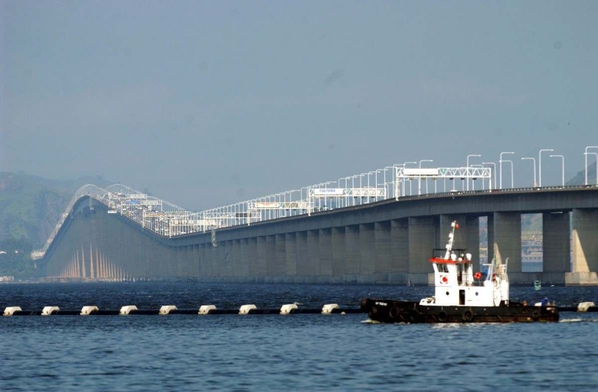 Ponte Rio-Niterói vista a partir do mar: em primeiro plano, há um barco que acaba de passar por baixo da estrutura, composta por centenas de pilares, sendo que vários deles, em perspectiva, são vistos em segundo plano