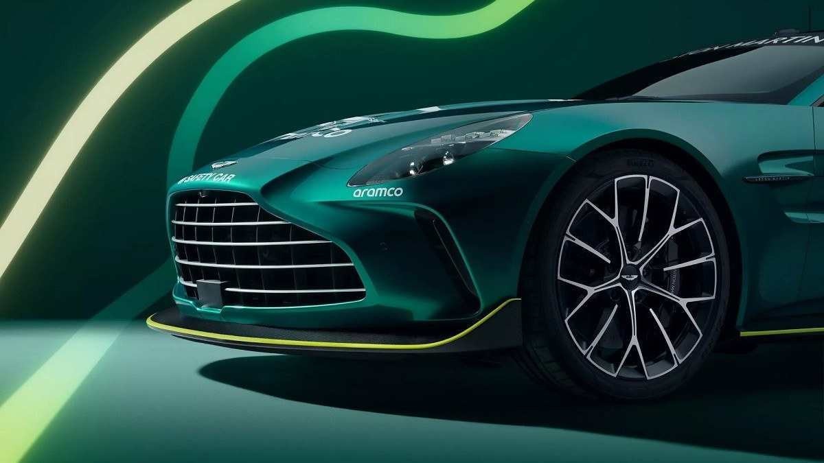 Dianteira do Aston Martin verde escuro plotado com adesivos de safety car em fundo verde e luz neon que remete a pista de corrida.