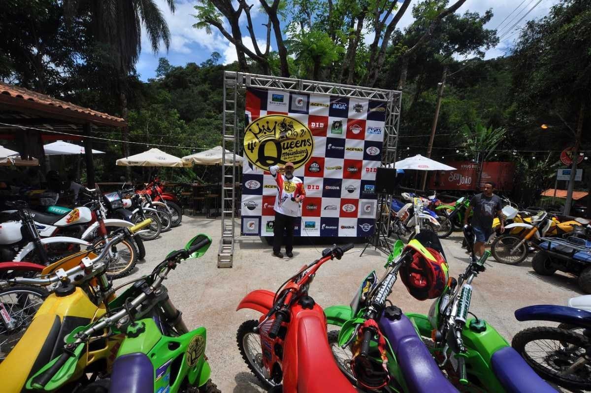 Visão geral do evento Queens of the Mountains, com várias motos estacionadas lado a lado, rodeando um banner quadriculado