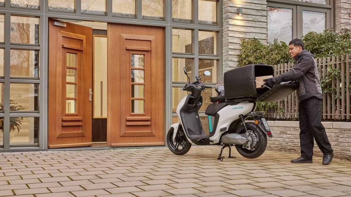 Yamaha Neo Delivery 2024 branco de traseira com baú aberto entregador tirando pizza na porta de uma casa