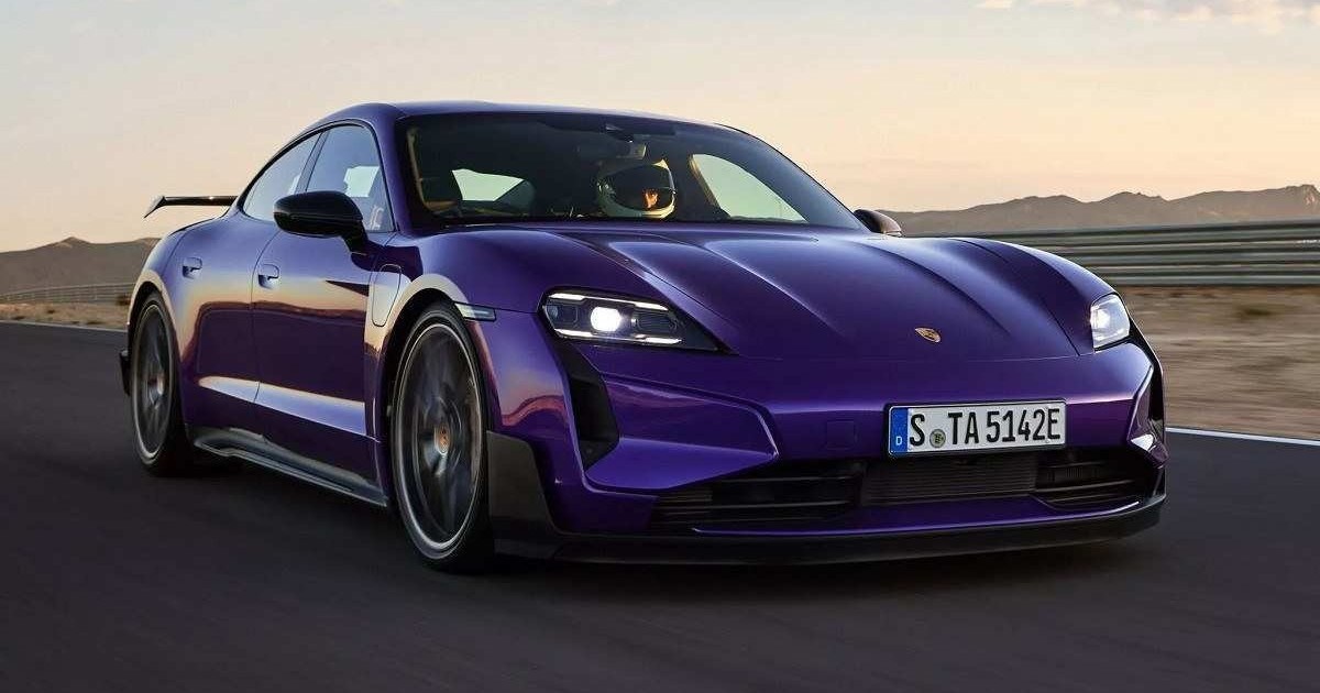 Porsche Taycan Turbo GT roxo visto de frente em uma pista de corrida com um céu amarelado ao fundo. 