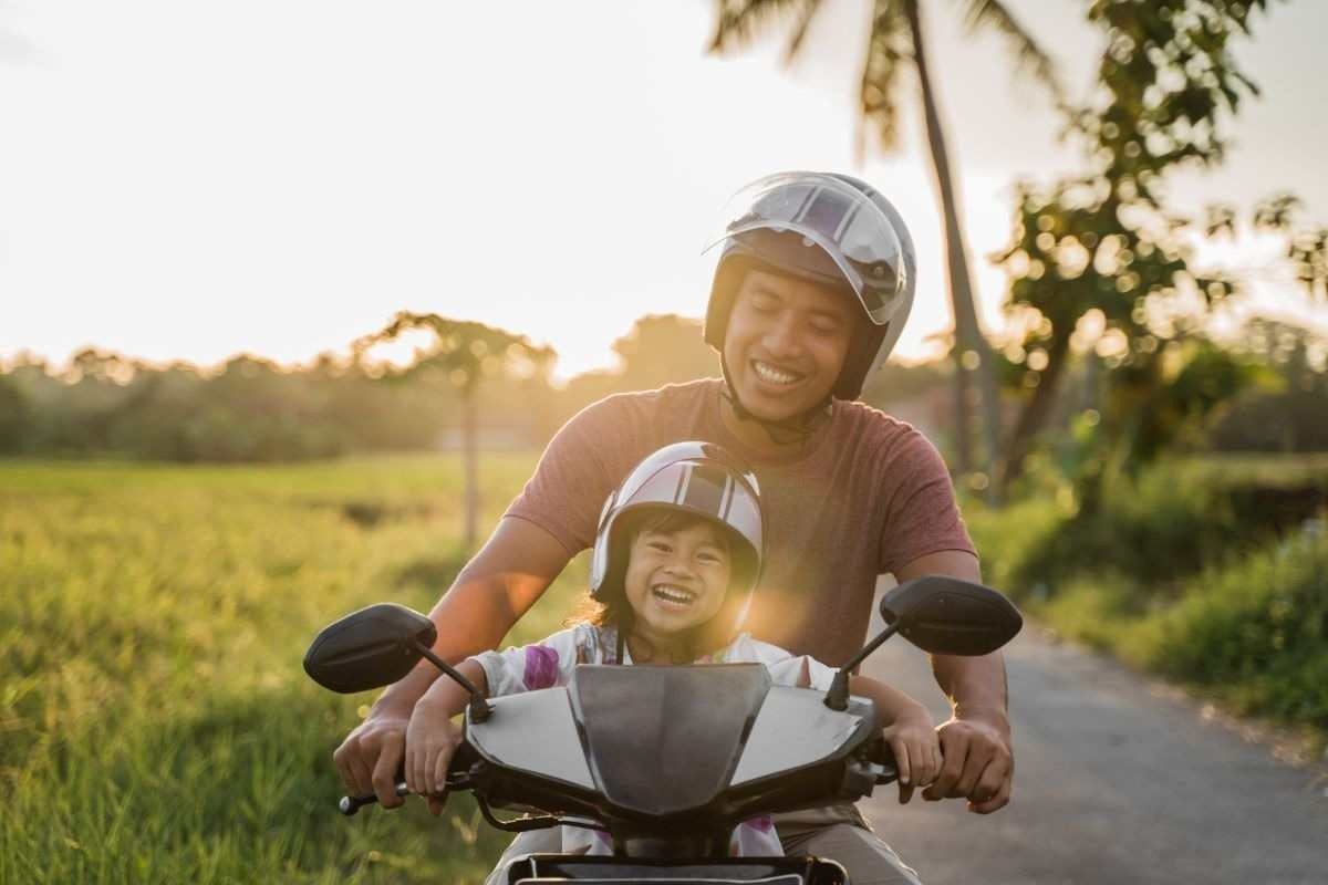 Pai e filho em motocicleta em movimento no asfalto
