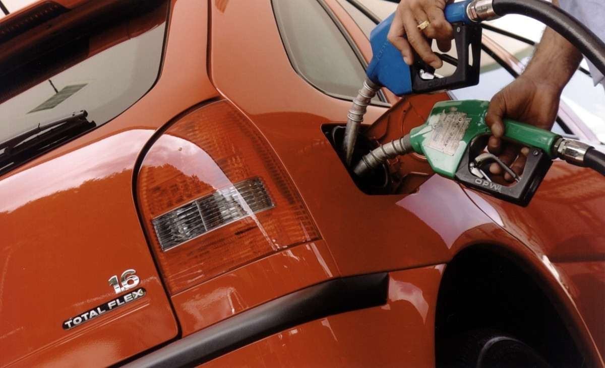 Bicos de duas bombas, de etanol e de gasolina, são introduzidos no bocal do tanque de um Volkswagen Gol Total Flex vermelho
