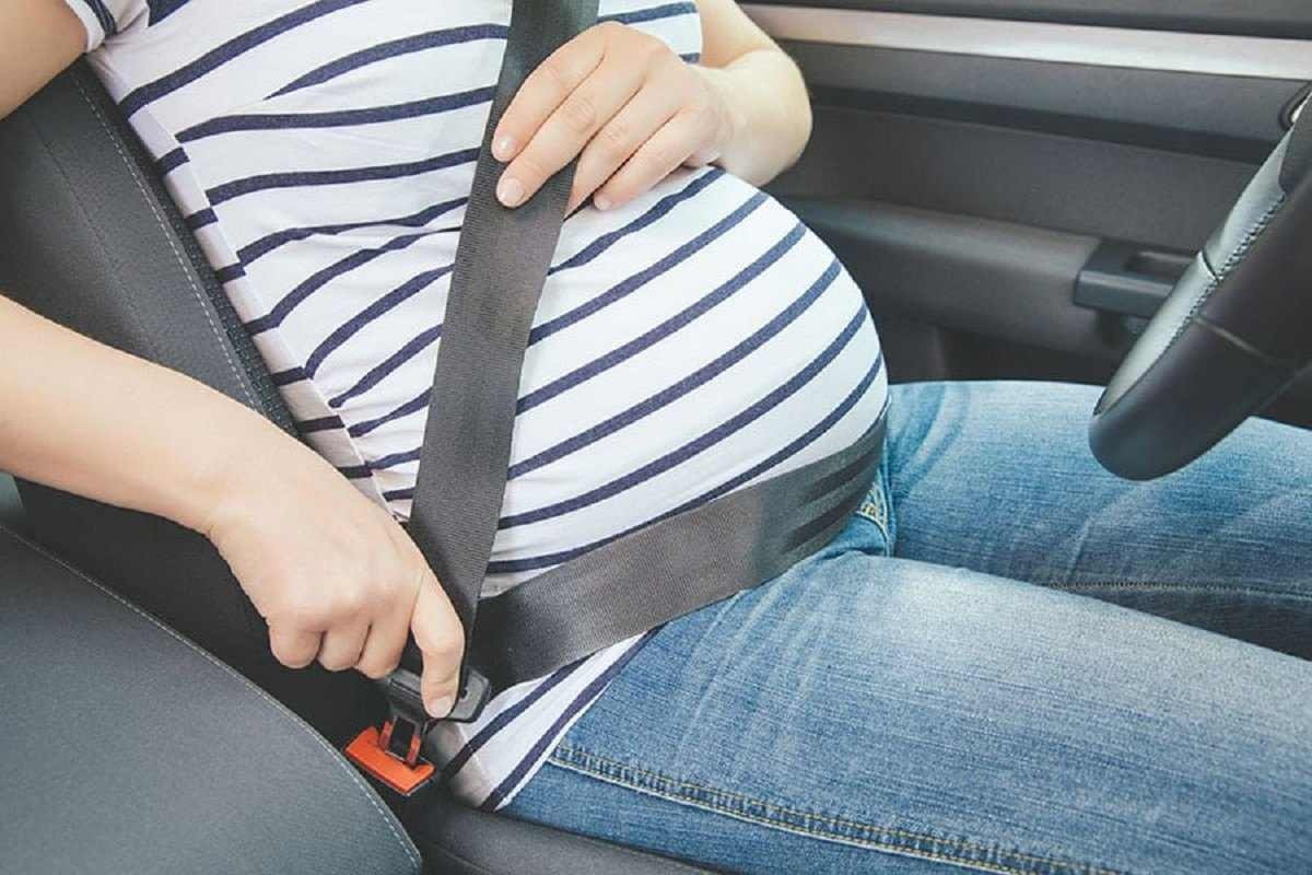 Mulher gravida colocando cinto de segurança em carro