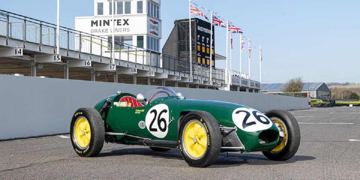 Lotus Type 12 verde escuro em pista de corrida com a dianteira apontando para a direita com arquibancada ao fundo.