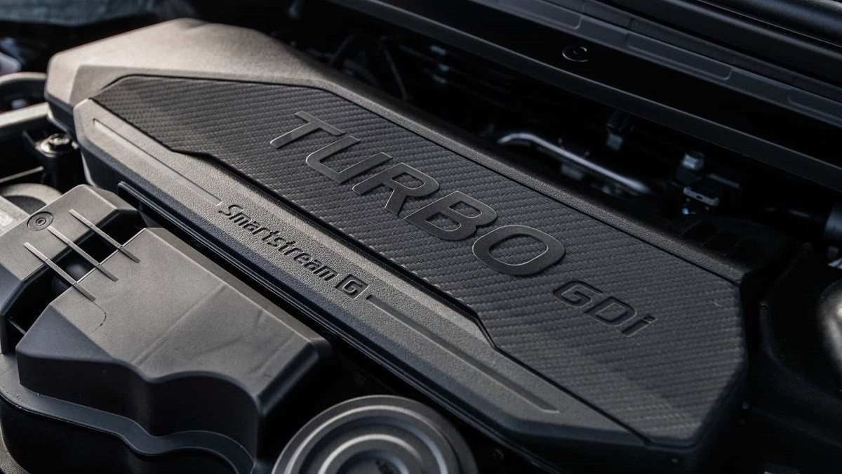 Motor do Kia K4 preto com letras também na mesma cor formando a palavra Turbo