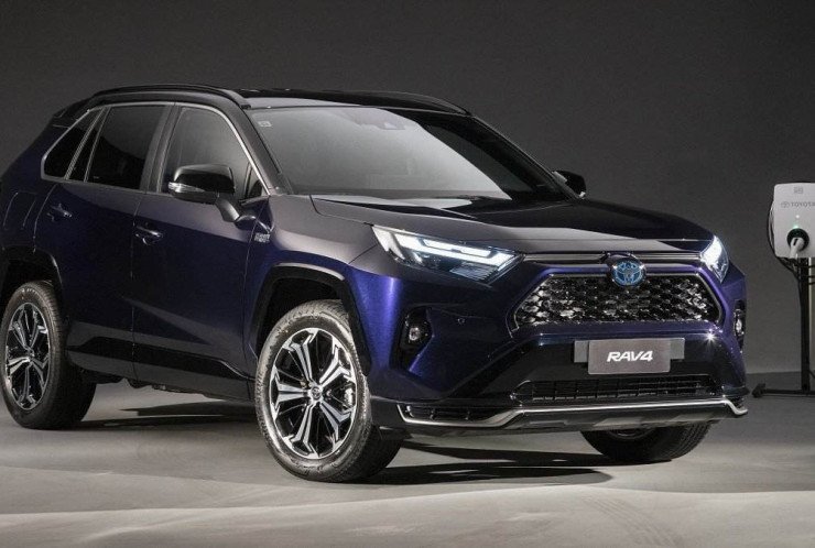 Toyota RAV4 XSE Plug-in Hybrid azul escuro isto pela dianteira sendo recarregado em wallbox em fundo preto.