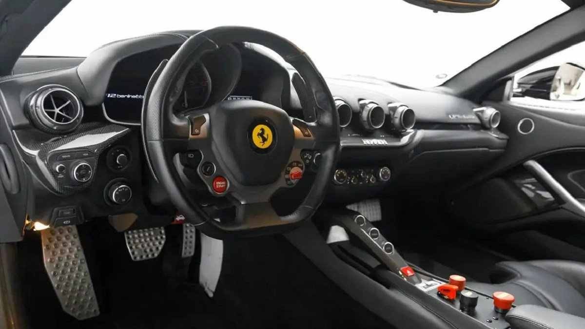 Console central e volante da Ferrari F12tdf com fundo branco sendo visto pelo para-brisa e janela lateral direita