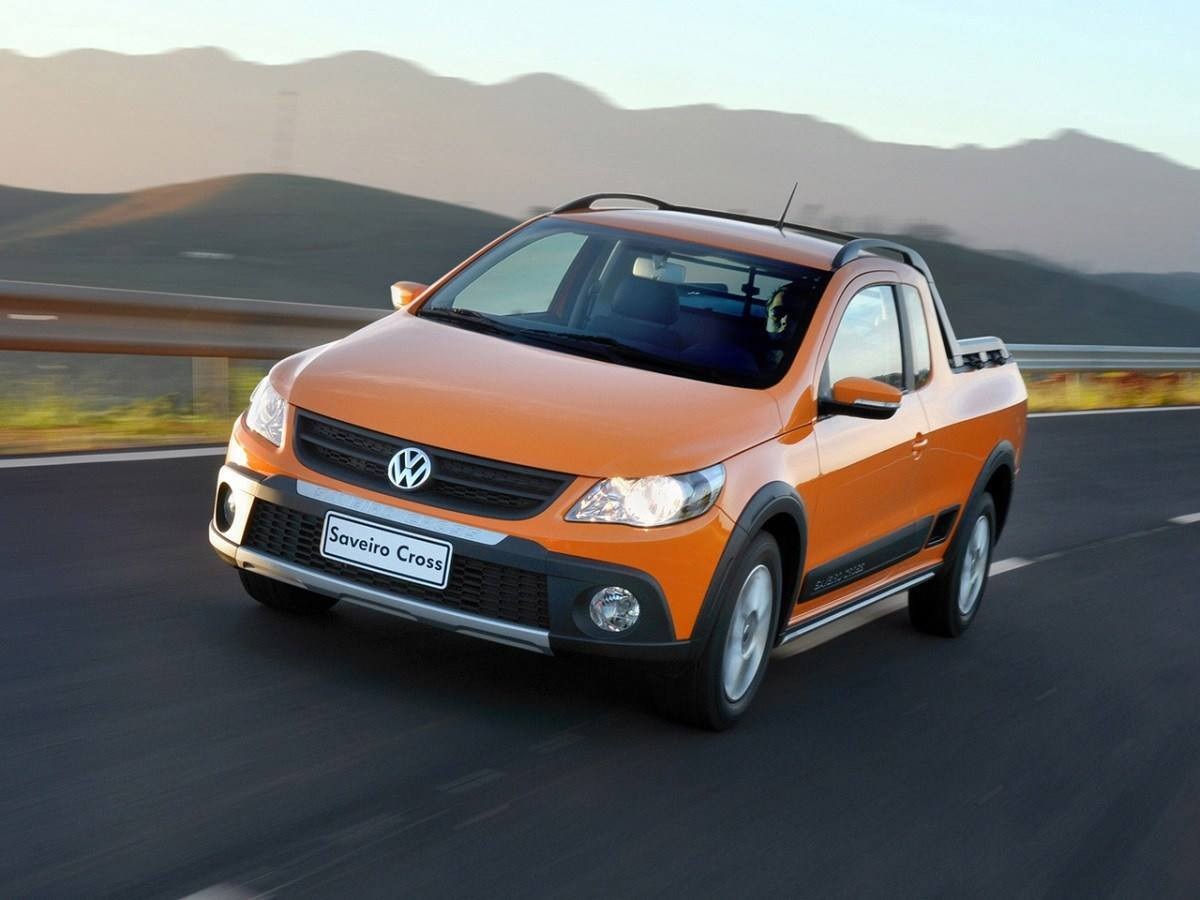 Volkswagen Saveiro modelo 2011 laranja de frente em movimento no asfalto