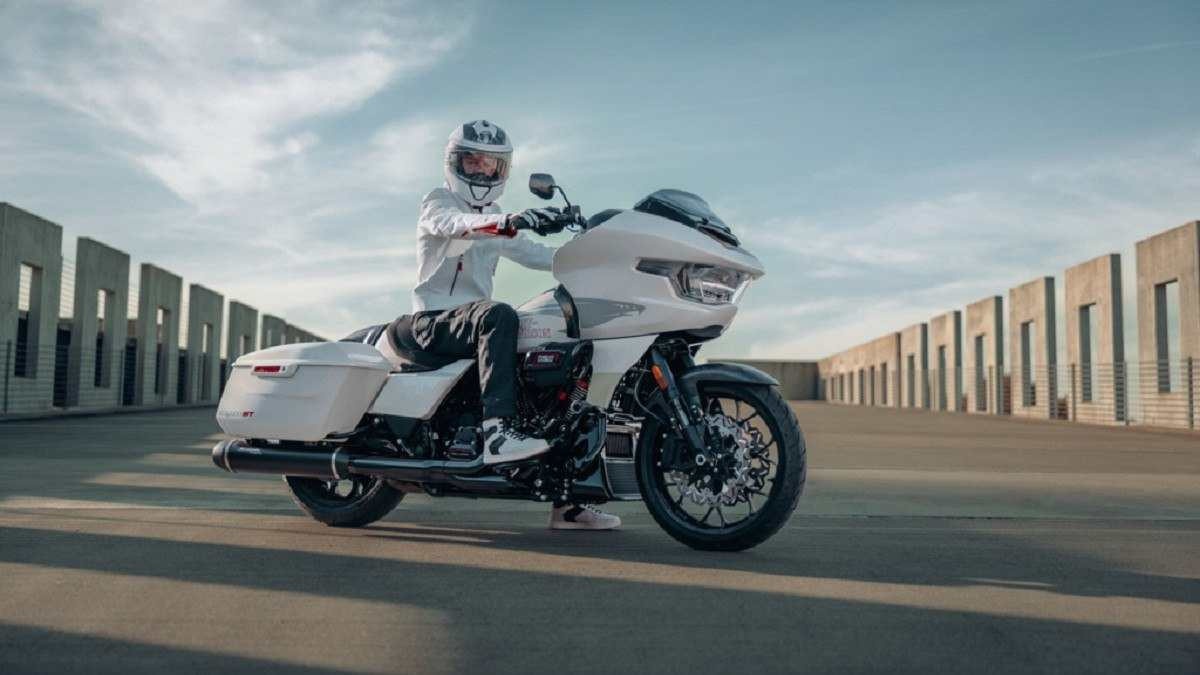 Harley-Davidson Road Glide ST branca com motociclista com roupas e capacete também brancos parado em ponte com céu claro e com poucas nuvens ao fundo