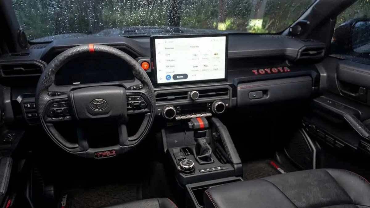 Interior do Toyota 4Runner em preto com pequenos detalhes em vermelho e tela no console central ligada