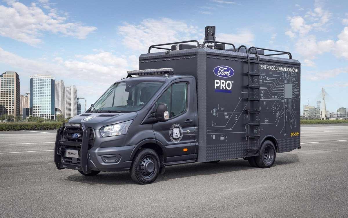 Ford Transit preparada para uso das forças de segurança, de frente, estacionado em local asfaltado. Veículo, que é adaptado para trabalhar como centro móvel de operações, é de cor cinza e traz a inscrição Força Tática na lateral.