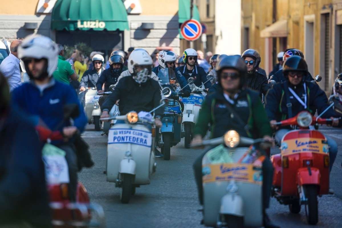 Piaggio Vespa vários modelos de diferentes cores e épocas em desfile de rua na Itália