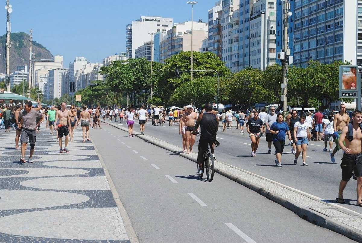 Avenida Atlântica, Rio de Janeiro, com várias pessoas caminhando, correndo e pedalando