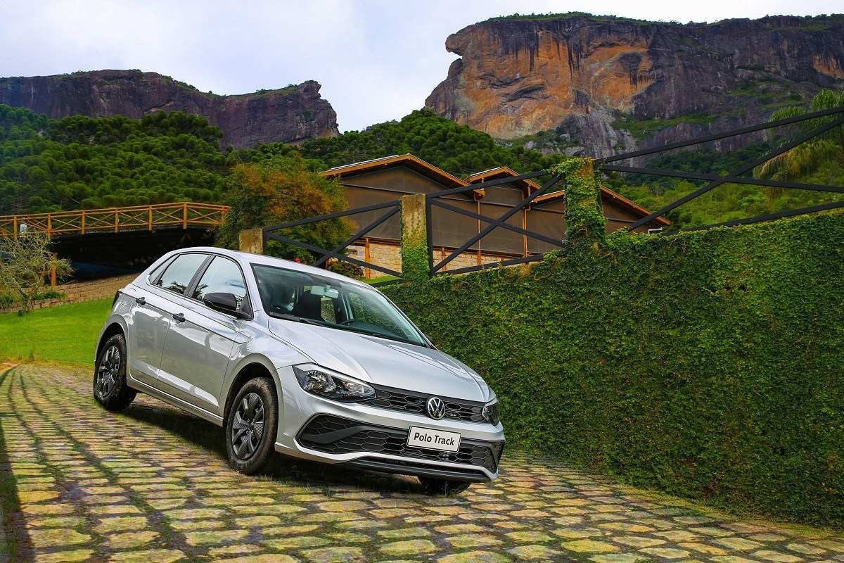 Volkswagen Polo Track 2023 cinza, de frente, estacionado em ladeira calçada com pedras, com cenário de montanhas ao fundo