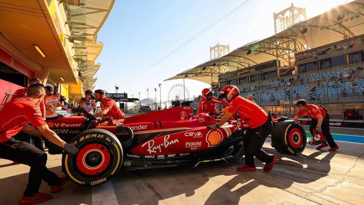 Modelo da Ferrari para corridas da Fórmula 1 sendo tocado por engenheiros da montadora em pit stop. Ao fundo é possível ver o céu claro com poucas nuvens