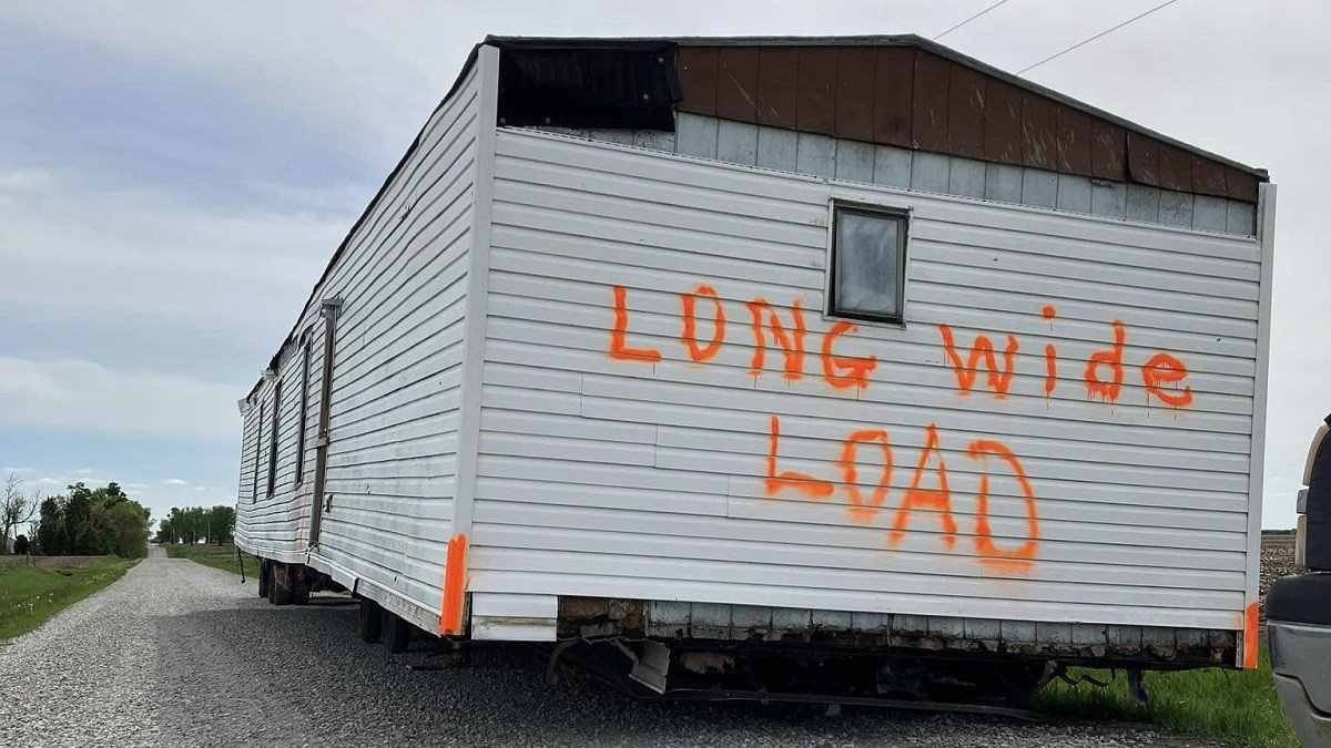 Casa rebocada branca pichada com 'Long wide load' em laranja